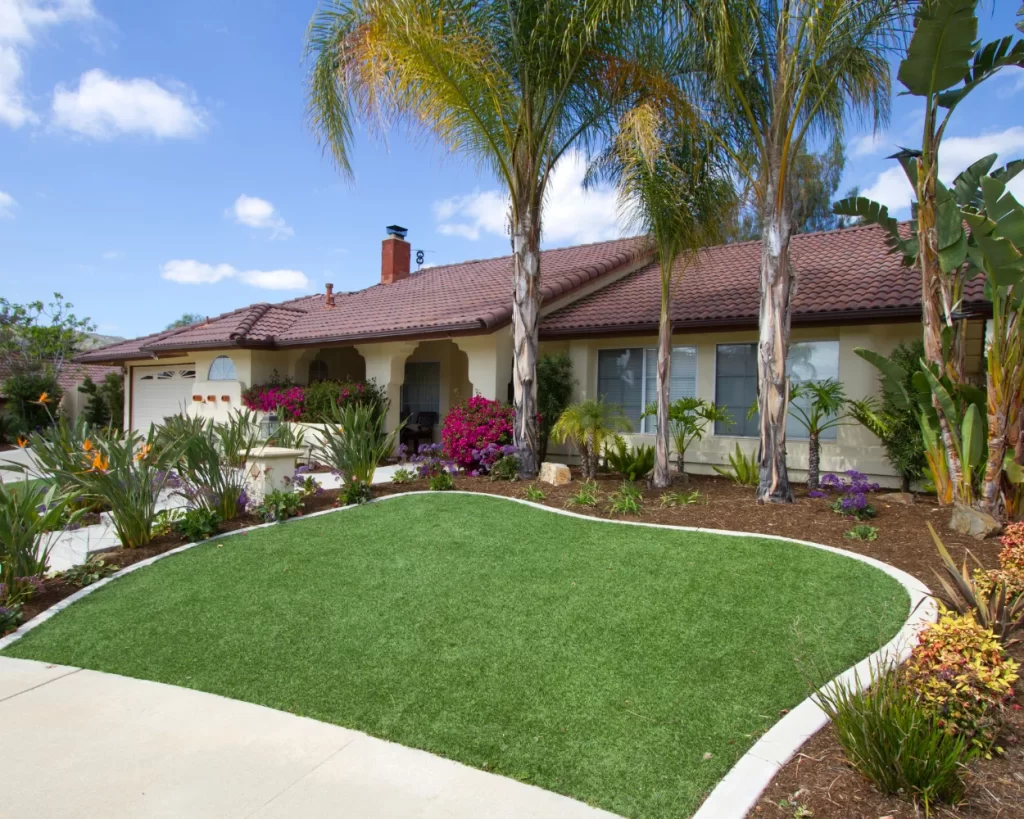 Front yard with artificial turf, tropical plants, and a well-maintained landscape design.